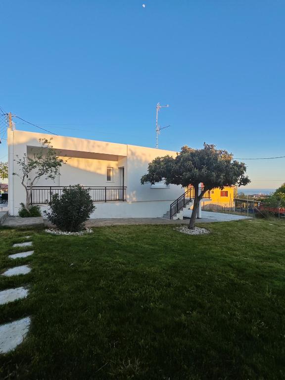 a white building with a tree in the grass at Giannis house in Makri