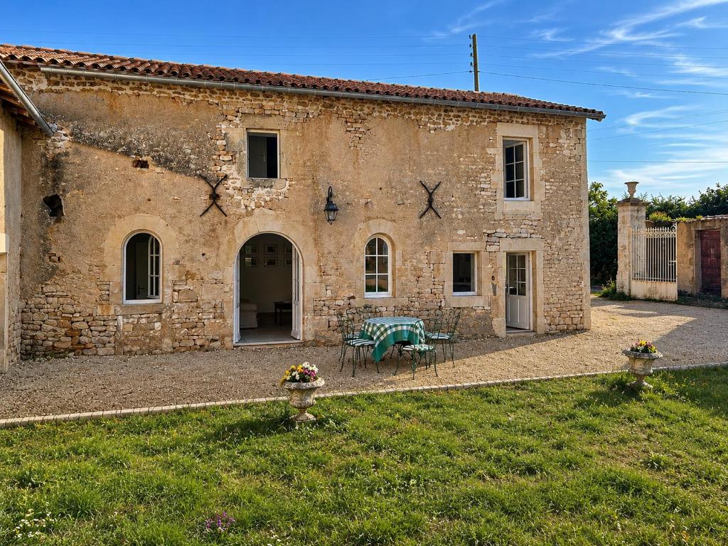 an old stone building with a table in a yard at Maison Mélusine in Londigny