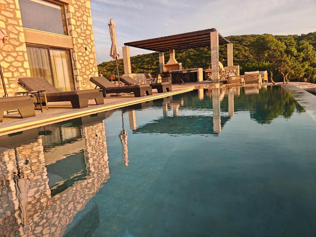a swimming pool with chairs and a house at Izel Villas in Skinária