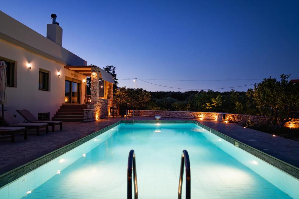 a swimming pool with lights in a backyard at night at Panorama Villa Sitia in Sitia