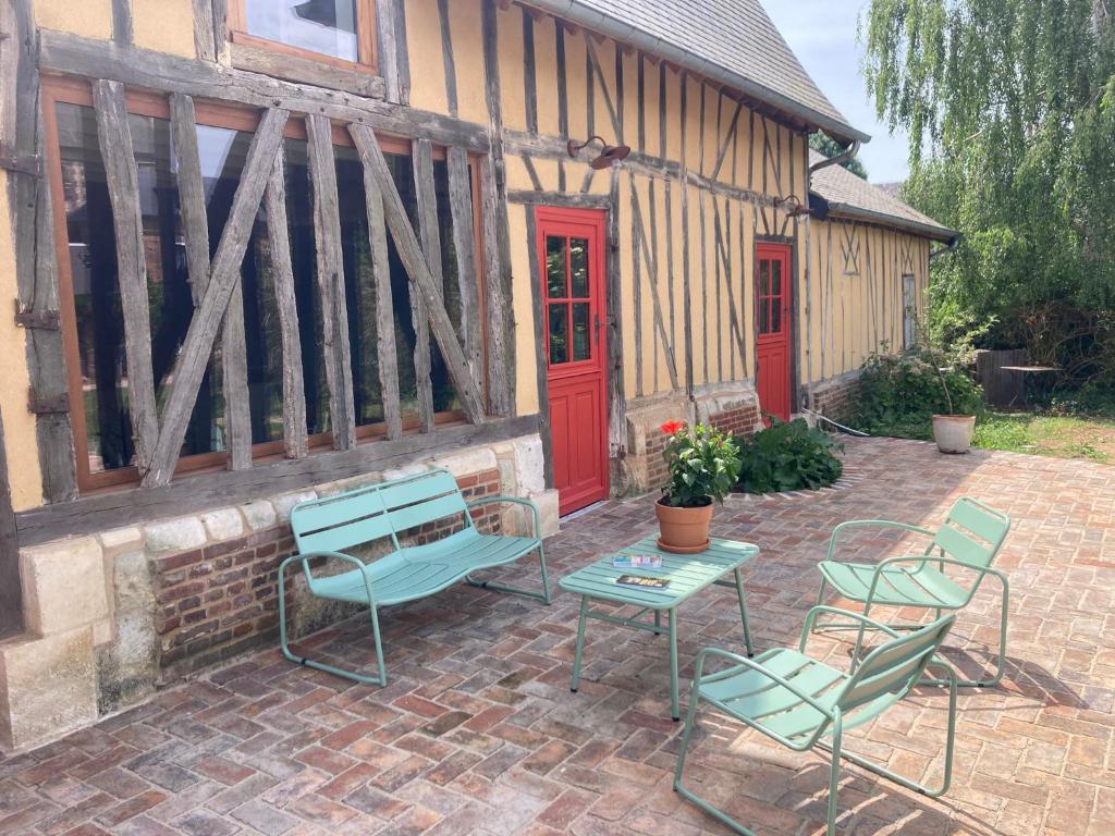 a patio with chairs and a table and a building at La Granch' - Maison d'hôtes in Harcourt