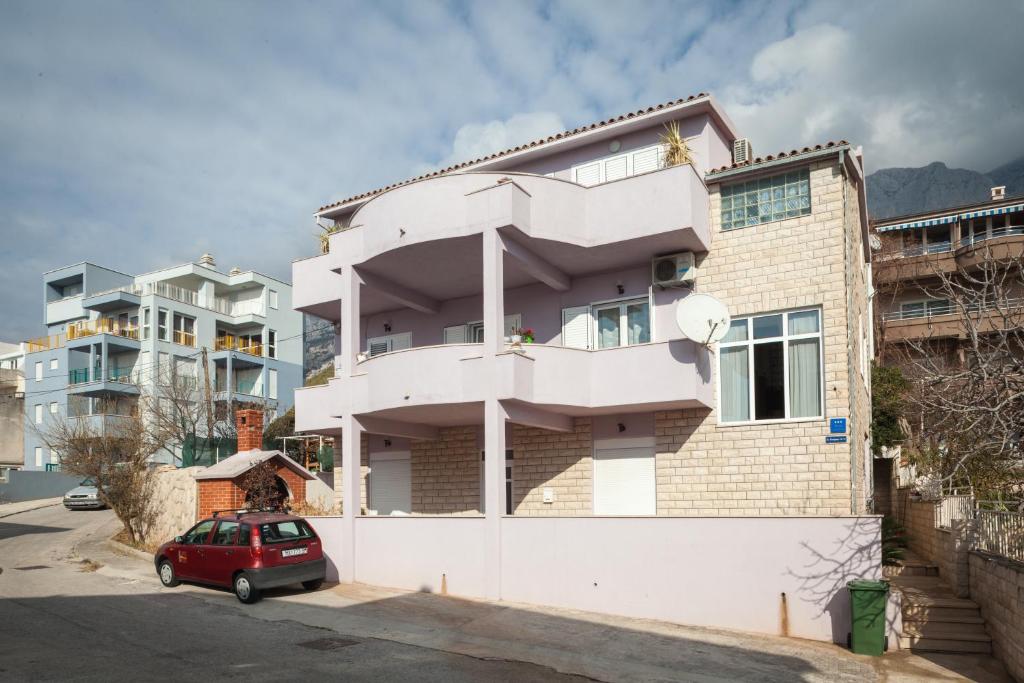 a house with a red car parked in front of it at Apartment Bešlić in Makarska