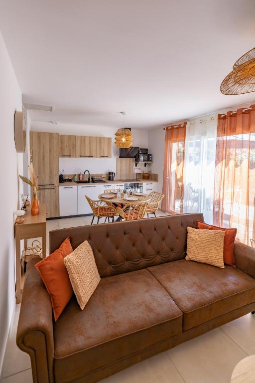 a living room with a brown couch and a kitchen at Terracotta house in Sorgues