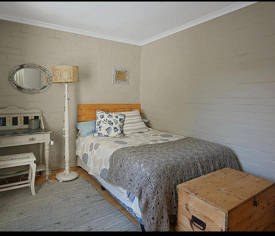 a bedroom with a bed and a lamp and a desk at Skulpie in Cape Town