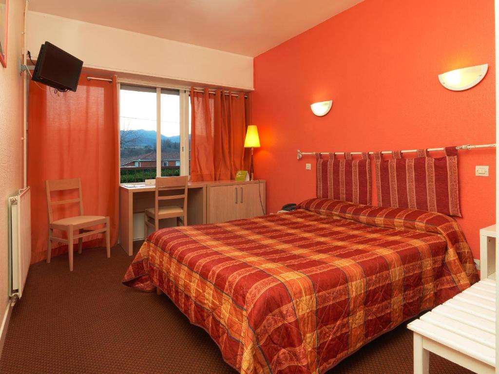 Habitación de hotel con cama, escritorio y ventana en Logis Hôtel restaurant Horizon 117, en Sentaraille