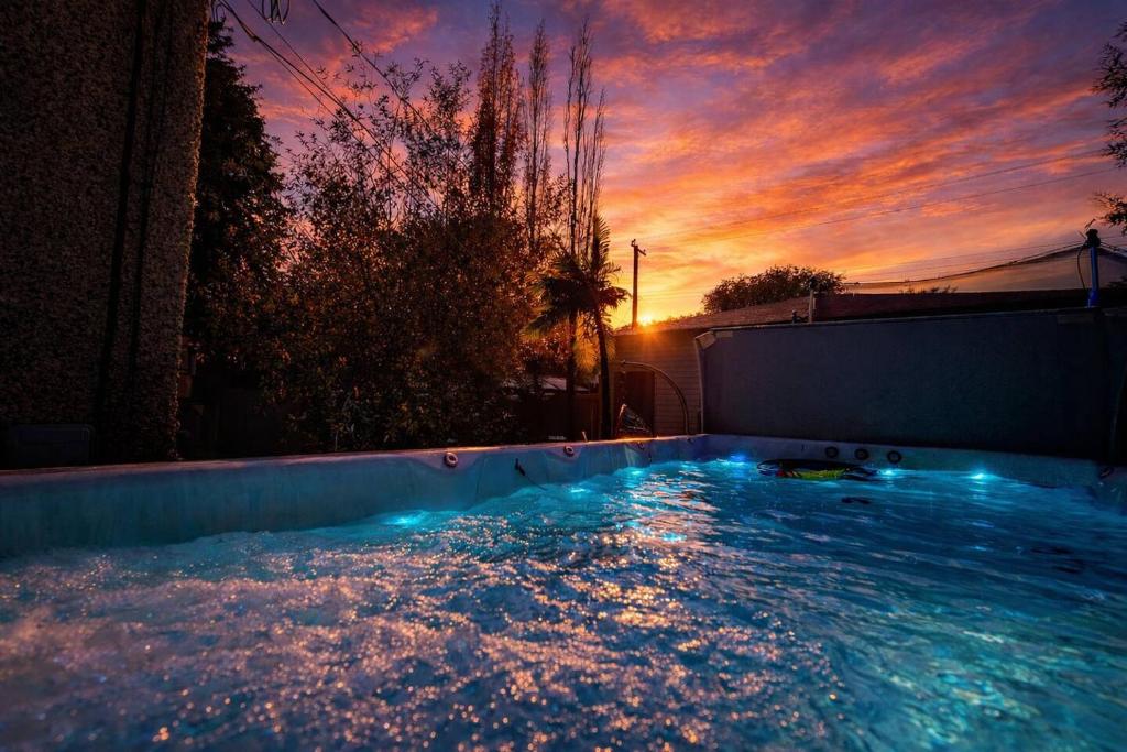 a large swimming pool with a sunset in the background at Urban Oasis - with 16ft Swim Spa - Heated Hot Tub & Pool in Edmonton