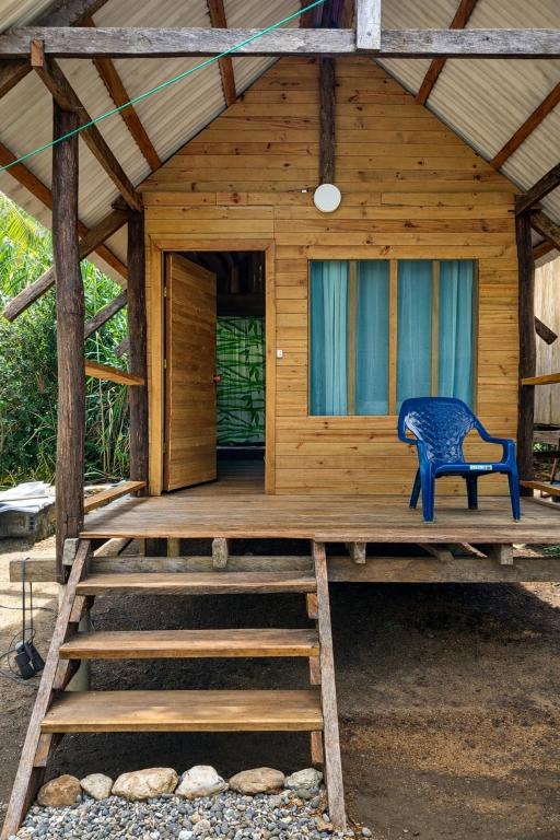a wooden cabin with a blue chair on the porch at Cabaña Vikana in Nuquí
