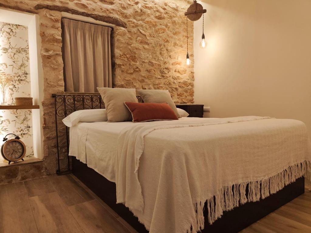 a bedroom with a large bed with a stone wall at Arrels Terra - Apartamento boutique mediterráneo in L'Ampolla