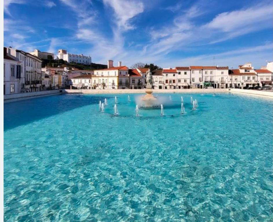 a large pool of blue water with buildings in the background at Casa dos Tios- Estremoz in Estremoz
