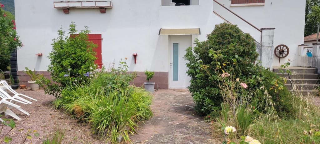 a white house with a red door and some bushes at Proche de la gare in Saint-Jean-Pied-de-Port