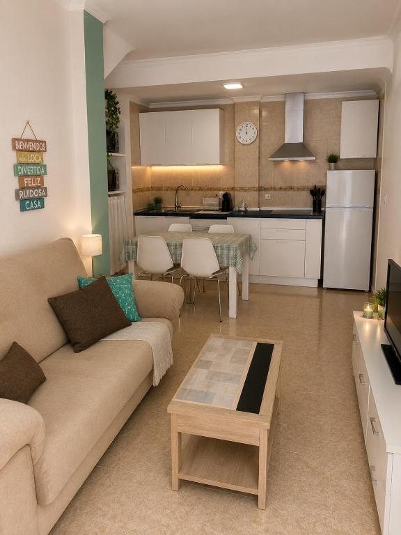 a living room with a couch and a table and a kitchen at Punta Umbria Apartment in Punta Umbría