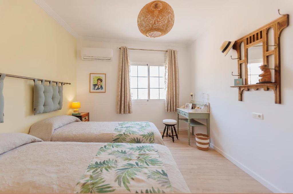 a bedroom with two beds and a desk and a window at Lumae Guesthouse in Lobres