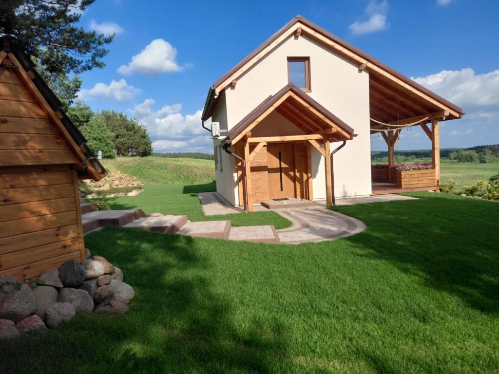 a house with a green lawn and a building at Nad Drwęcą in Mszano