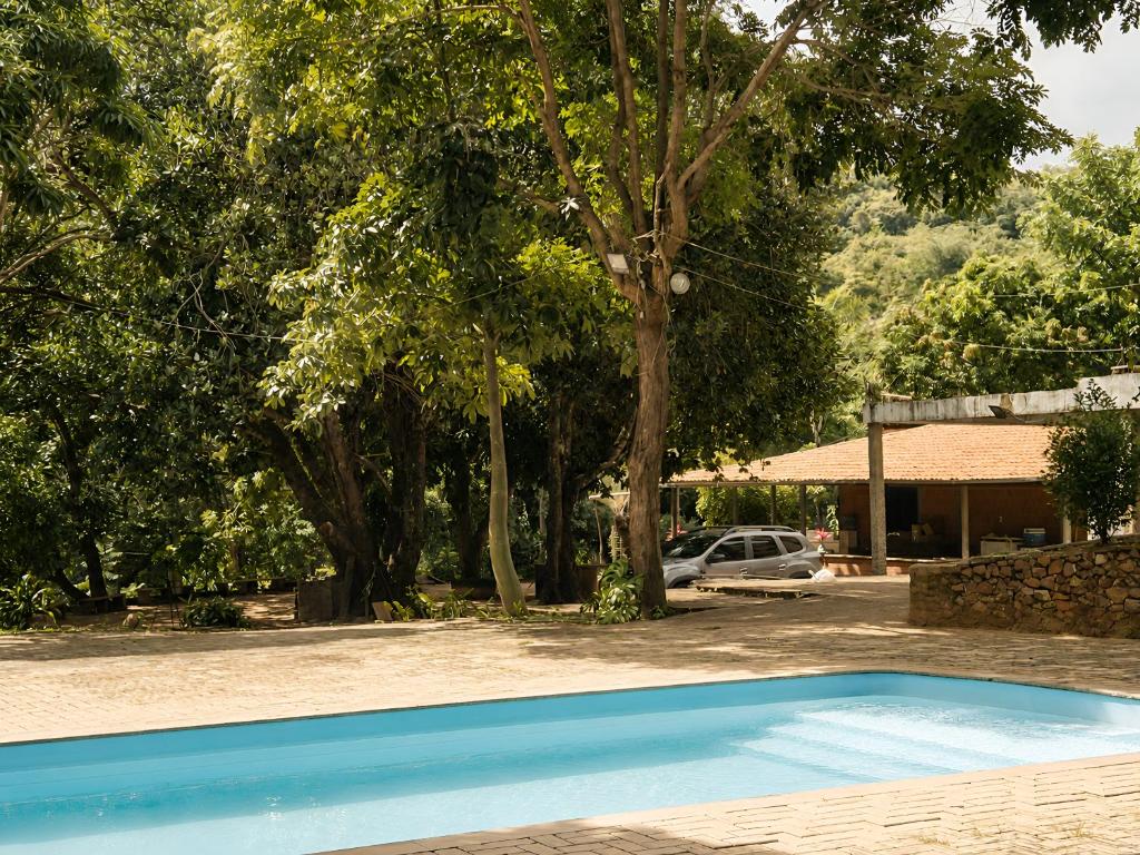 a blue swimming pool in a yard with trees at Refúgio na Serra à 15min do Centro in Crato