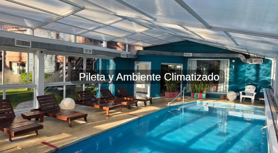 a swimming pool with chaise lounges and chairs next to a building at La Posta de Cariló in Carilo