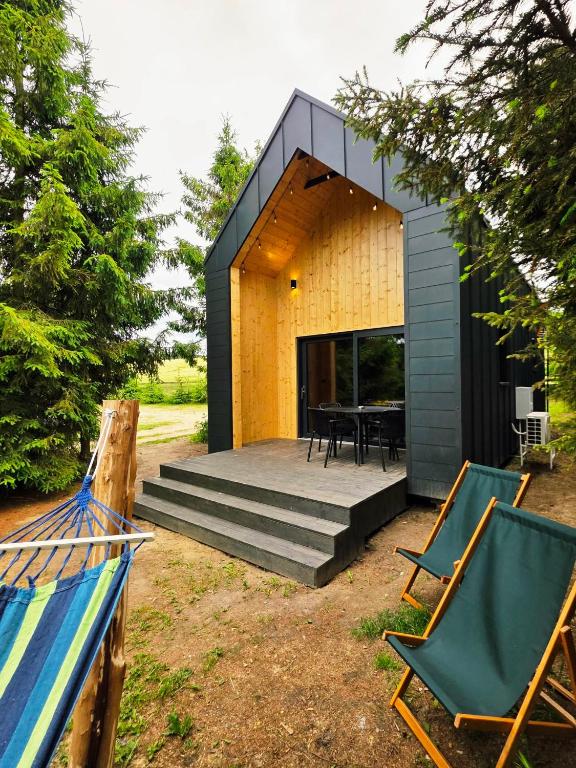a tiny house with a black roof and two chairs at Domek Daglezjowy in Małe Leżno