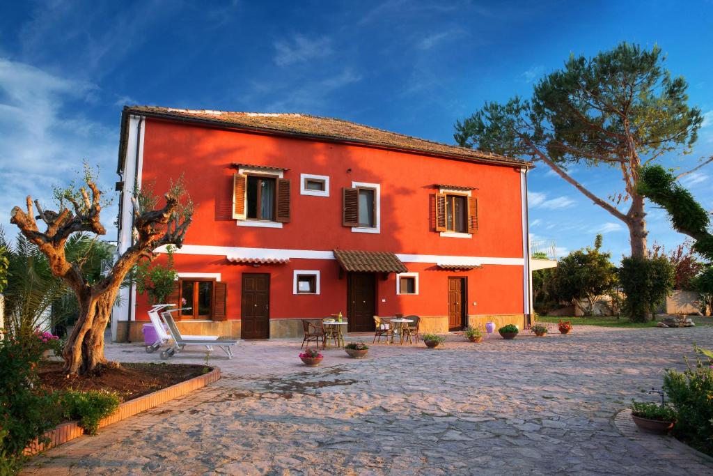 una casa rossa con un patio di fronte di B&B La Chora Di Paestum a Paestum
