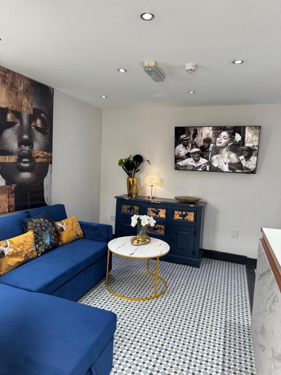 a living room with a blue couch and a table at Secret Garden Suite in Gloucestershire