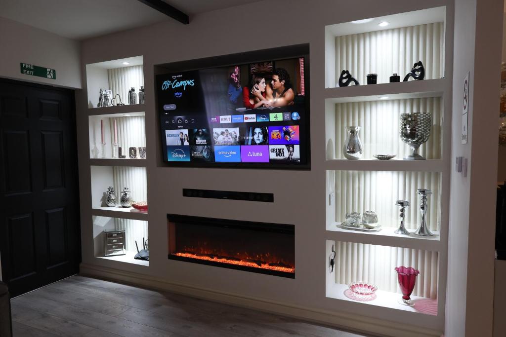 a living room with a fireplace and a flat screen tv at Pasture Side House in Clayton