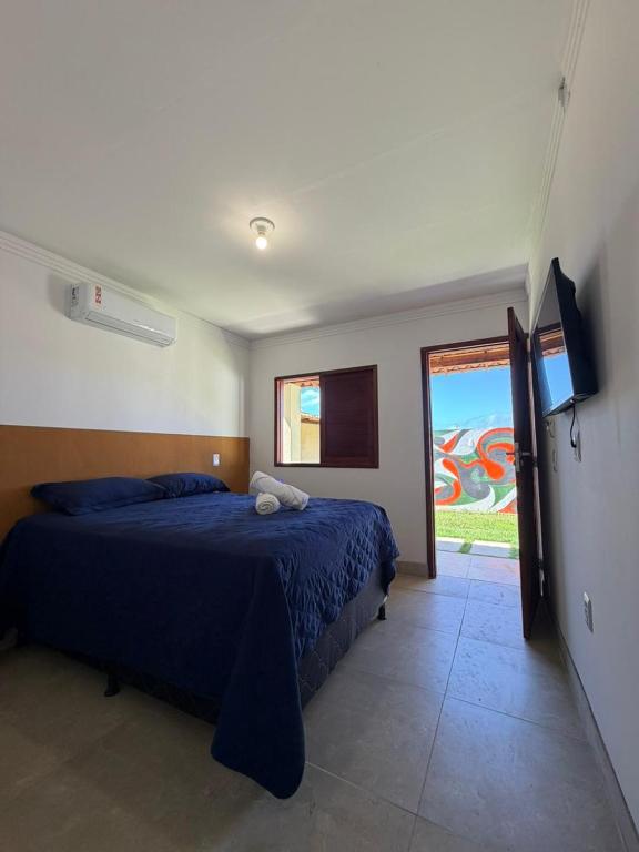 a bedroom with a blue bed and a sliding glass door at Brisa da Mata Suítes BF quarto 02 in Baía Formosa