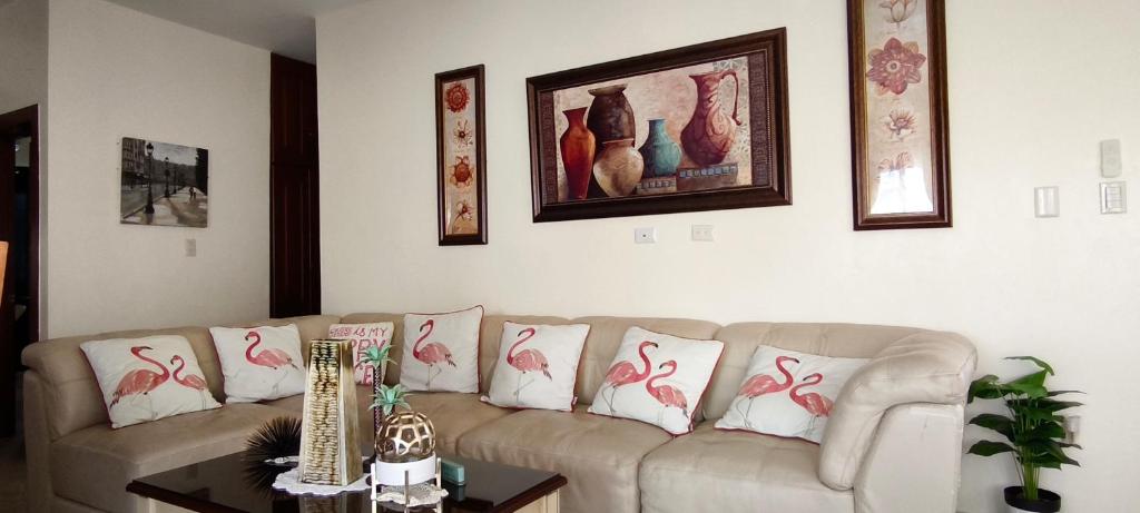 a living room with a couch with pink flamingos pillows at Caribbean Luxury Penthouse in San Felipe de Puerto Plata