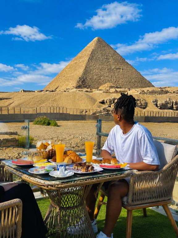a woman sitting at a table in front of a pyramid at Gaillon Scarab Pyramids View in Cairo