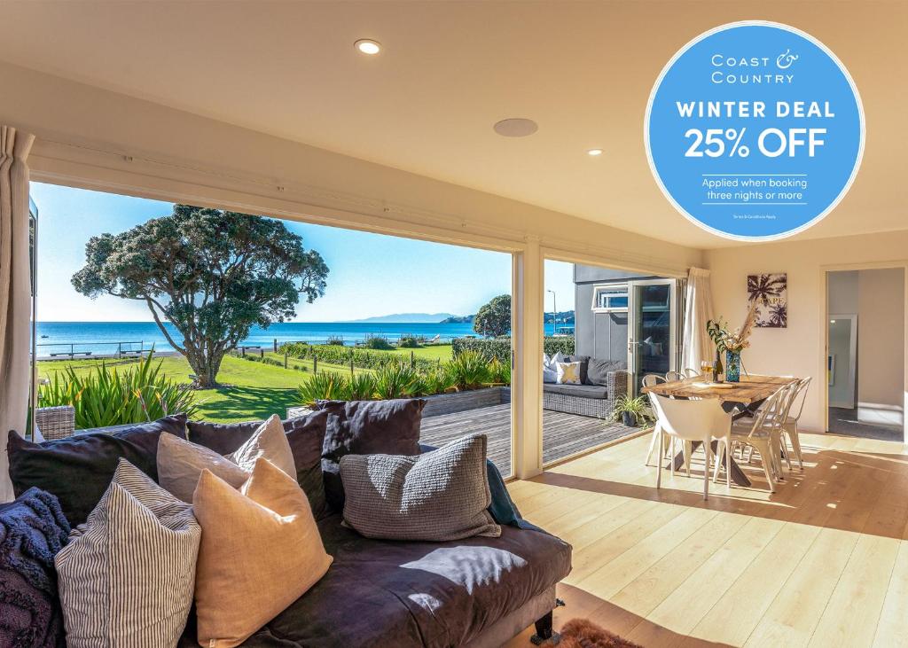 a living room with a couch and a view of the ocean at Onetangi Beachfront Escape - Coast & Country in Onetangi