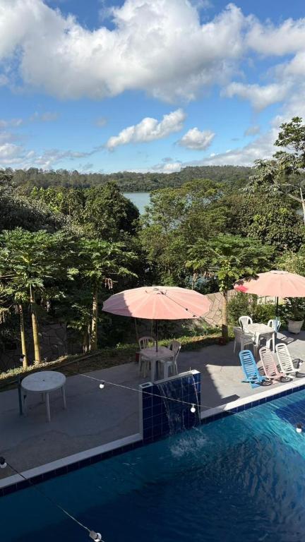 a swimming pool with two umbrellas and a table and chairs at Tucanos Club in São Paulo
