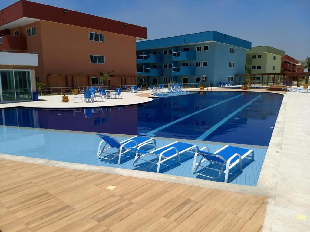 a swimming pool with blue chairs in front of a building at GOLDEN LAKE, lugar para relaxar in Arraial do Cabo