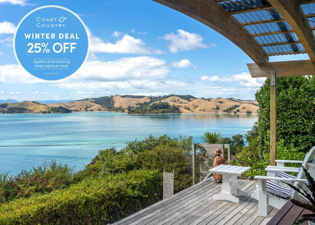a man sitting on a deck looking out over a lake at The Sanctuary Couples Retreat in Waiheke Island