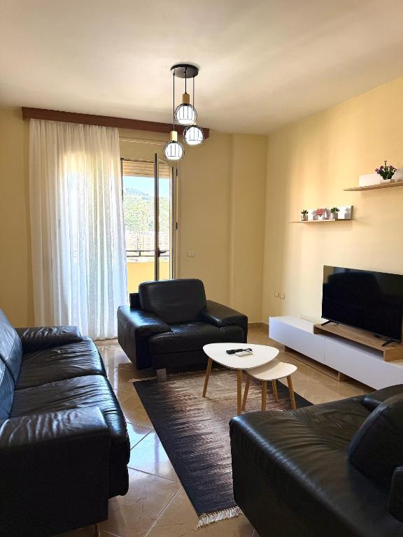 a living room with black leather furniture and a tv at Vlora Center Apartment - 5 Min to Lungomare in Vlorë