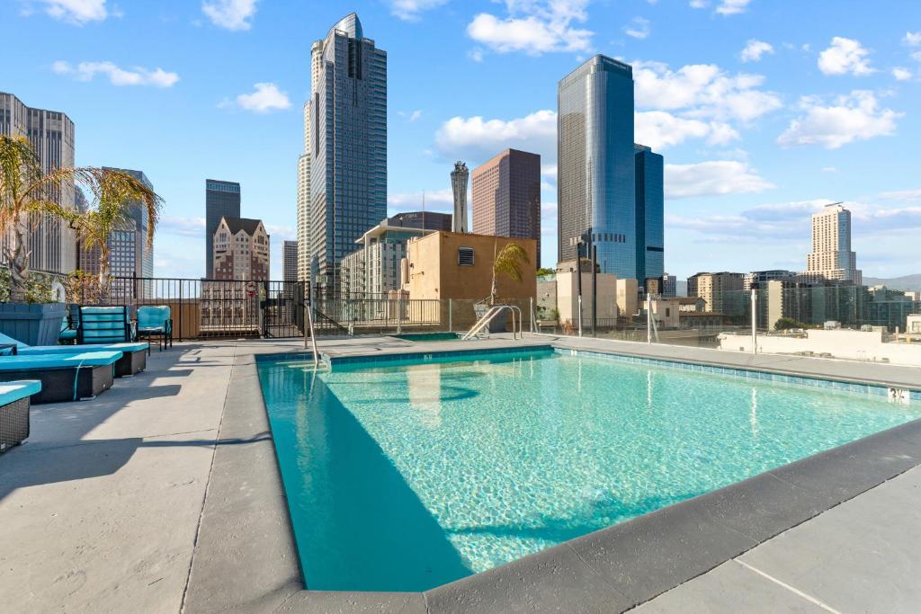 a swimming pool with a city skyline in the background at Rooftop Pool & City Views! Long-Term Dtwn LA Stay in Los Angeles