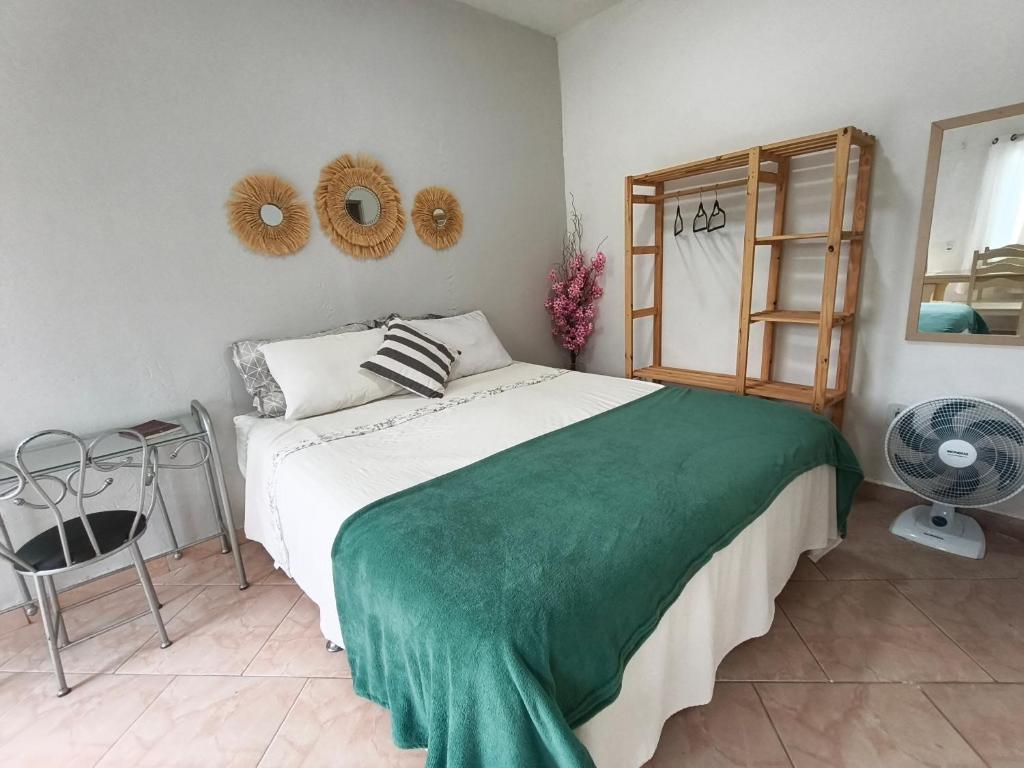 a bedroom with a bed with a green blanket on it at Solares Boa Estada in Búzios