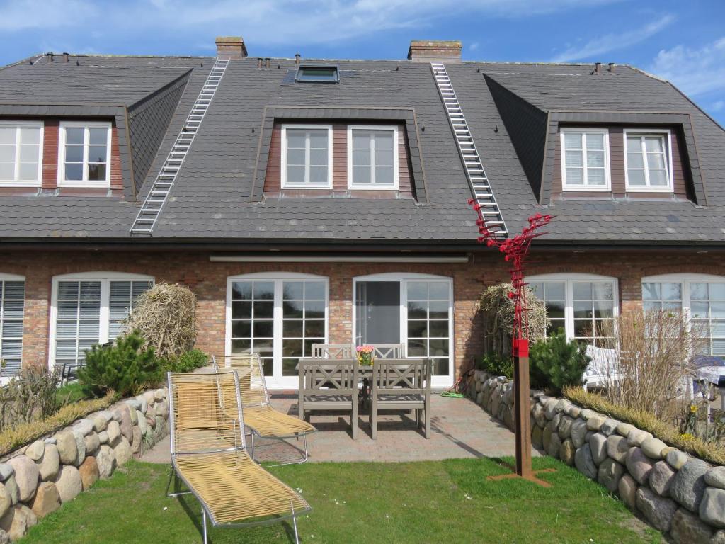 a house with two chairs and a table in the yard at Ferienhaus Weetstich in Archsum