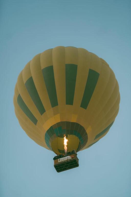 a yellow and green hot air balloon in the sky at Luxor hot air balloon co in Jazīrat al ‘Awwāmīyah