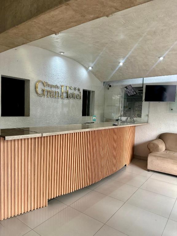 a room with a counter with a kitchen and a couch at Pequeno Gran Hotel in Aguascalientes