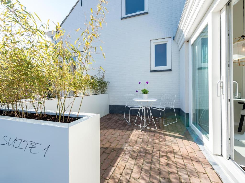 a small patio with a table on a white house at Zilte Suite in Oostkapelle