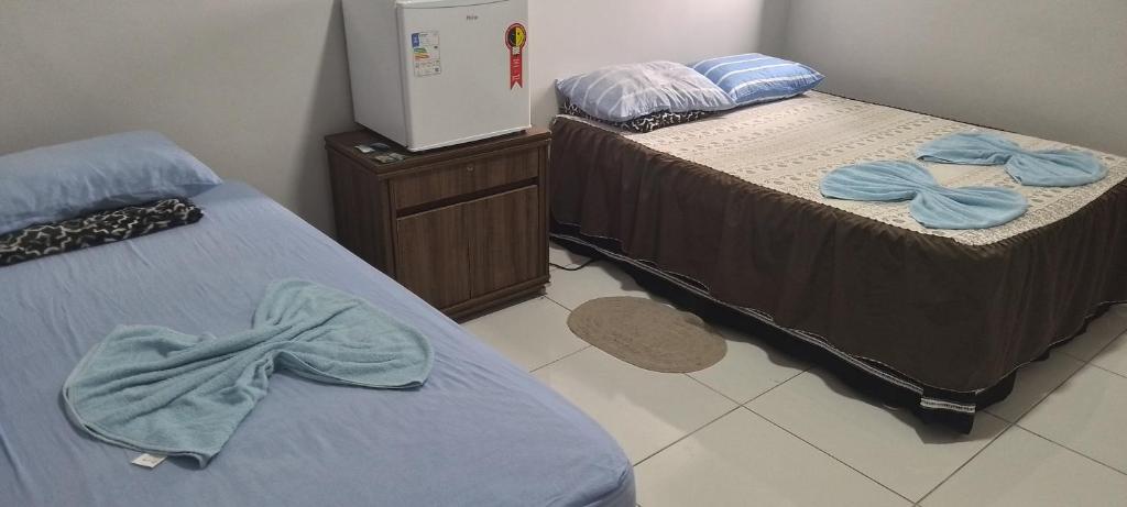 two beds in a room with towels on them at Pousada santa Clara in Matão