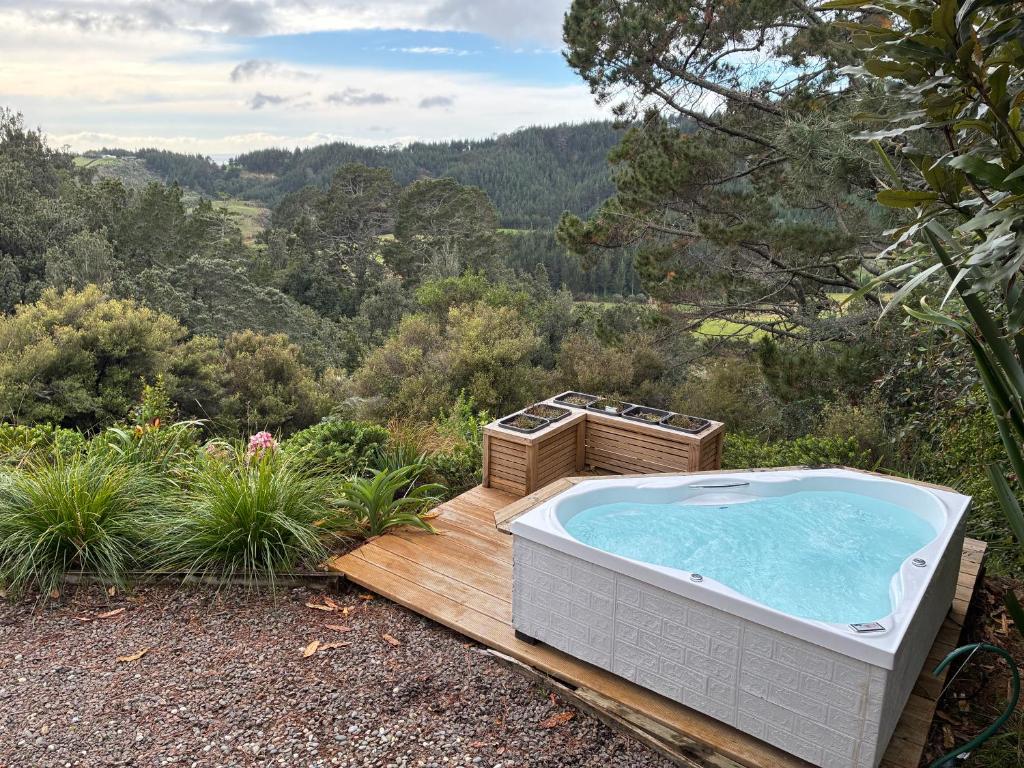 a jacuzzi tub on a wooden deck in the woods at Fantail Point - secluded cabin with stunning views and outdoor bath in Upper Papamoa