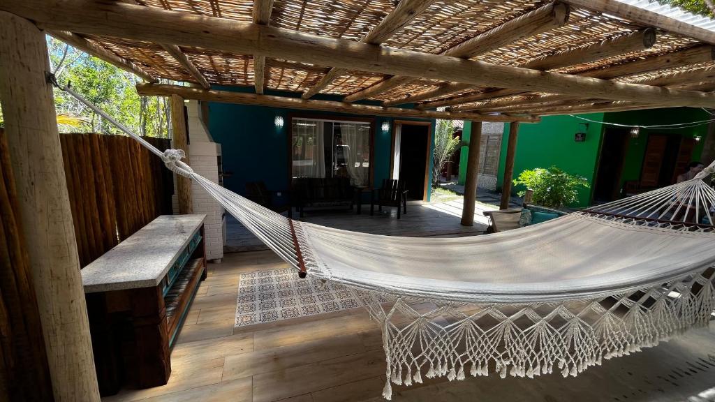 a hammock hanging from a pergola on a porch at Chalé Paraíso Corumbau - Chalés Uvas Azul in Corumbau