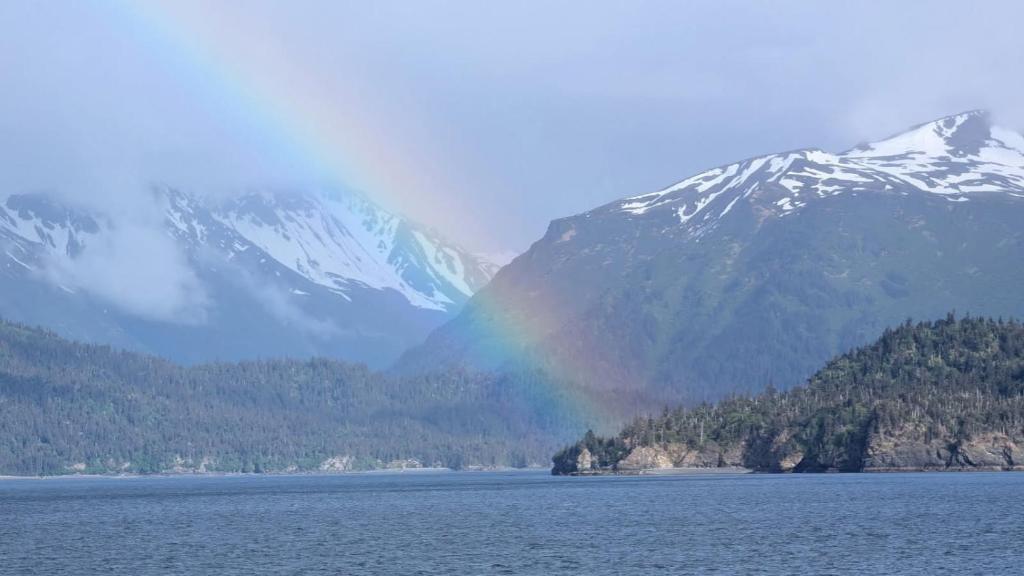 a rainbow over a lake with mountains in the background at Sea Parrot Inn in Seldovia