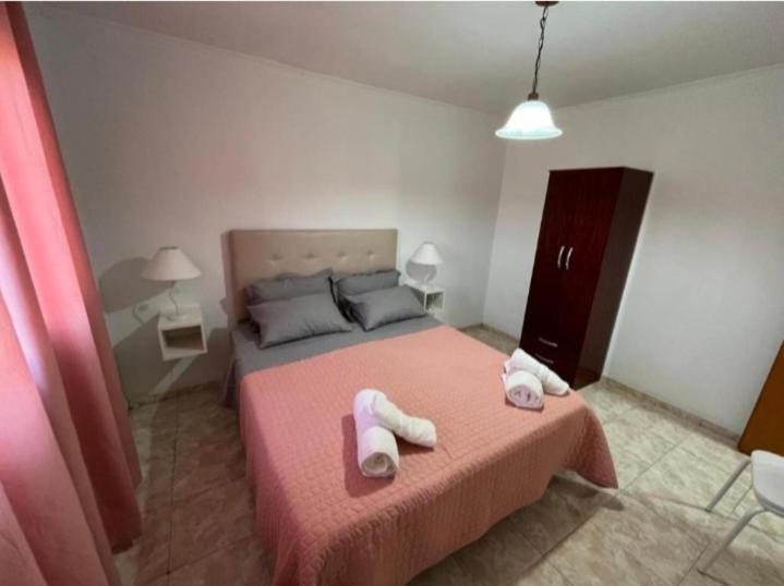a bedroom with a pink bed with towels on it at Departamentos en Chivilcoy in Chivilcoy