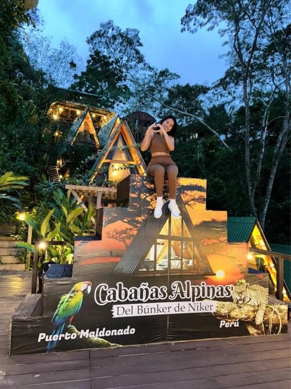 a woman sitting on a sign taking a picture at Bunker de niker in Puerto Maldonado