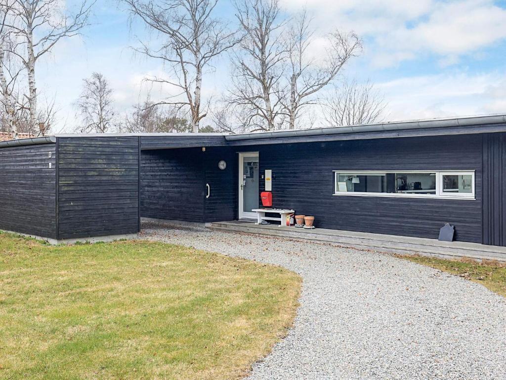 a black house with a gravel driveway at sunny Cottage with Spa facility in Gedser