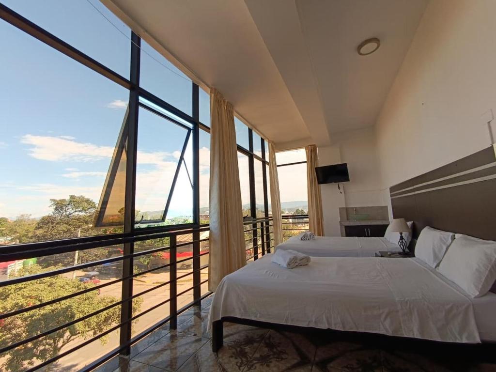 a bedroom with two beds and a large window at Hotel Valle Verde in Tarapoto