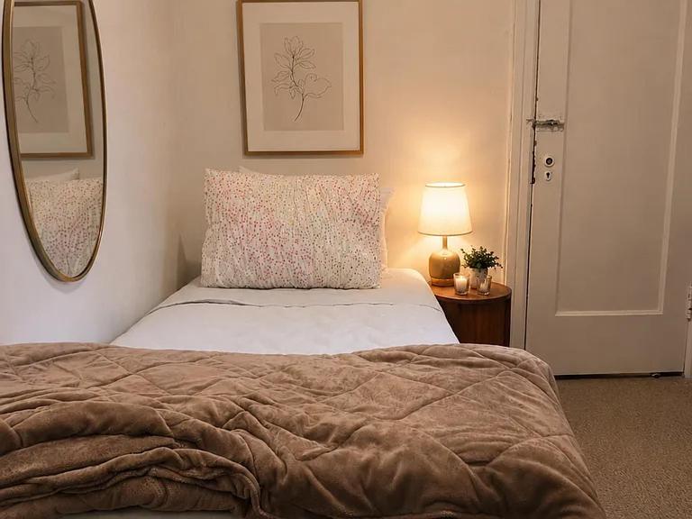 a bedroom with a bed and a lamp and a mirror at Luxury Pre-War Townhouse Bronx 5BR in University Heights