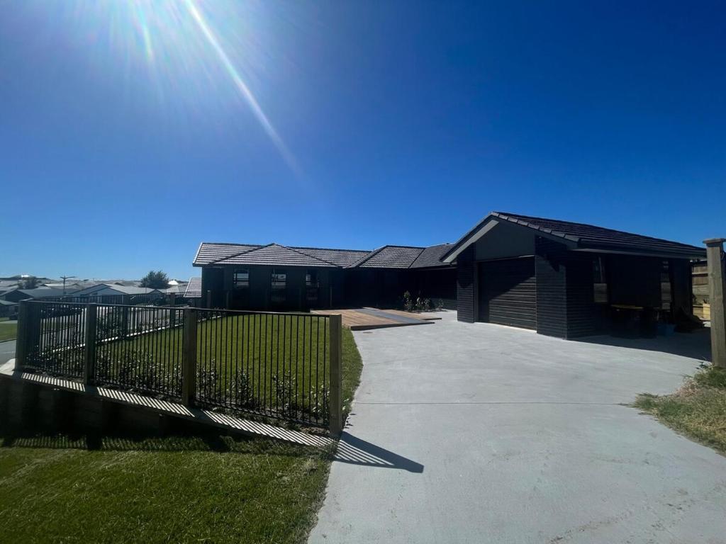 a house with a fence in front of a driveway at Sweet Serendipity in Tauranga