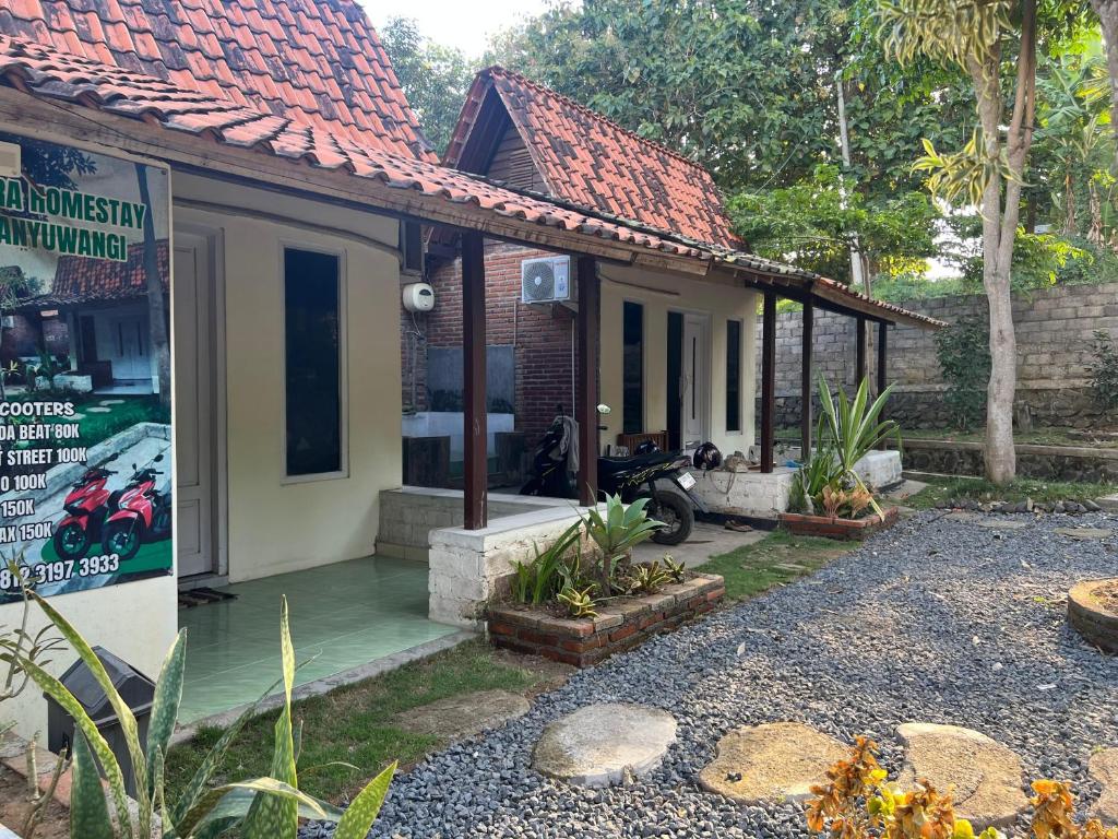 a small house with a motorcycle parked in front of it at Tiara Homestay Banyuwangi Near train Station in Banyuwangi