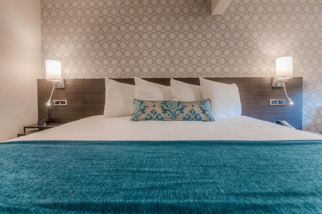 a bedroom with a large bed with a green blanket at The Hotel Y, a Dazzler Select by Wyndham in Yakima