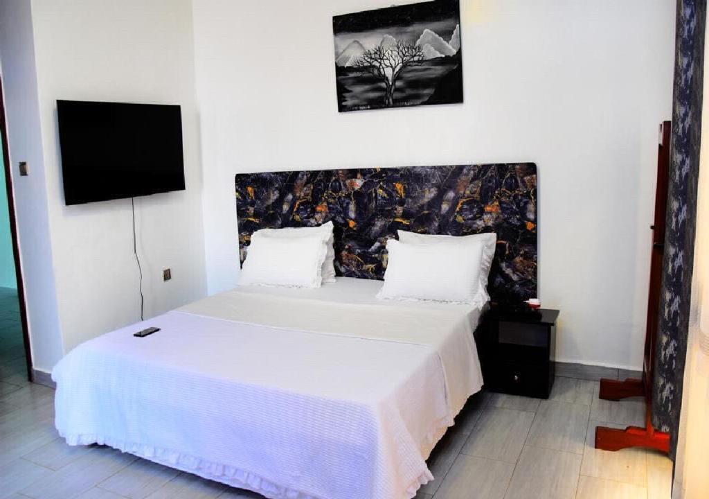 a bedroom with a white bed with a tv on the wall at KiGALI CLASSIC LODGE in Kigali